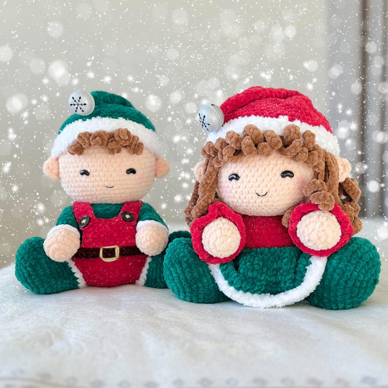 K&ouml;nnte beinhalten: Zwei geh&auml;kelte Pl&uuml;schtiere, eines als Elf in Gr&uuml;n und Rot gekleidet, das andere als Weihnachtsfigur in Rot und Gr&uuml;n.
