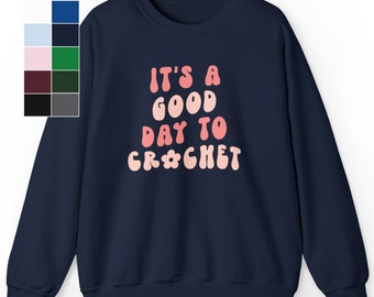 Puede incluir: Sudadera azul marino con el texto "It's a good day to crochet" en letras rosa y blancas.