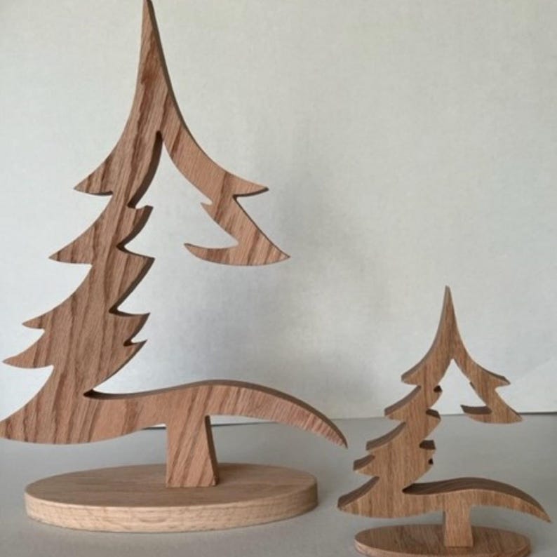 May include: Two wooden Christmas tree ornaments, one large and one small, with a cutout design. The trees are made of light brown wood and stand on a round base.