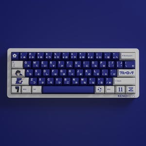 Könnte beinhalten: Eine mechanische Tastatur mit weißen und marineblauen Tastenkappen. Die Tastatur verfügt über japanische Zeichen und englische Buchstaben. Die Leertaste und die untere Reihe sind marineblau. Die Tastatur hat den Text "KENOKEYS" unten rechts.