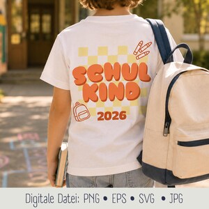 Könnte beinhalten: Ein weißes T-Shirt mit einem gelben Karomuster auf der Rückseite, bedruckt mit dem orangefarbenen Text "SCHUL KIND" und "2026" darunter. Das Design enthält orangefarbene Strichzeichnungen von drei Buntstiften und einem Rucksack, getragen mit einem beigen und marineblauen Rucksack.