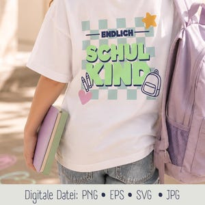 May include: A white t-shirt featuring a light blue and white checkered square background with the text ENDLICH SCHULKIND in large green letters. The design includes a yellow star, a pink heart, two crayons, and a small backpack illustration.