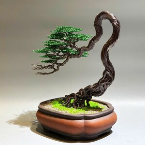 May include: A wire sculpture of a bonsai tree with green leaves and a brown pot. The tree is made of twisted wire and has a realistic appearance.