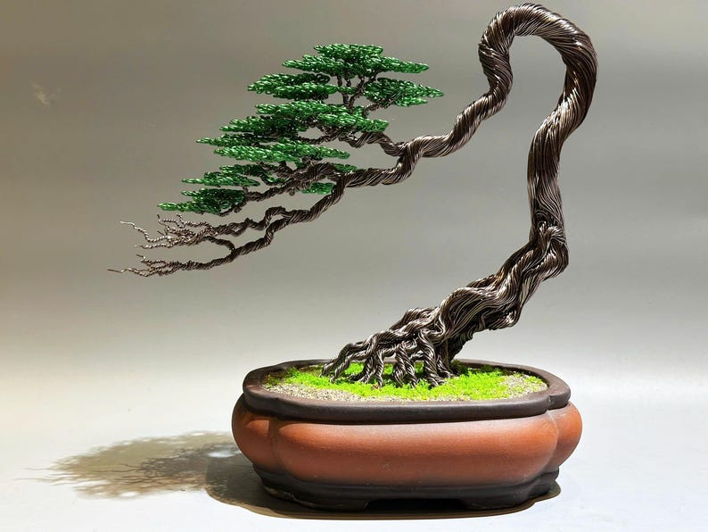 May include: A wire sculpture of a bonsai tree with a green foliage and a brown pot. The tree is made of twisted wire and has a realistic appearance.