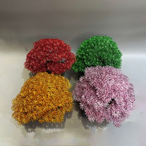 Puede incluir: Cuatro &aacute;rboles bonsai de alambre en diferentes colores: rojo, dorado, rosa y verde. Los &aacute;rboles est&aacute;n hechos de alambre y est&aacute;n dispuestos en un cuadrado.