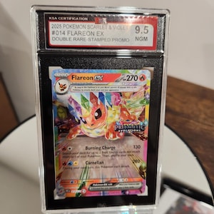 May include: A graded Pokémon card featuring Flareon EX from the 2025 Scarlet & Violet set. The card is a double rare-stamped promo, graded 9.5 by KSA. The card art showcases a colourful Flareon with the text "Burning Charge" and "Carnelian".