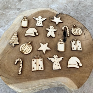 Peut inclure: Divers ornements de Noël en bois, dont un sapin, une étoile, un ange, une bougie, un coffret cadeau et un sucre d'orge. Les ornements sont disposés sur une surface en bois.