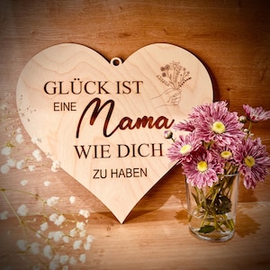 Könnte beinhalten: Ein herzförmiges Schild aus Holz mit dem Text "Glück ist eine Mama wie dich zu haben" und einem floralen Design.