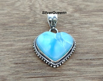May include: A silver heart-shaped pendant with a light blue gemstone. The pendant has a detailed silver border.