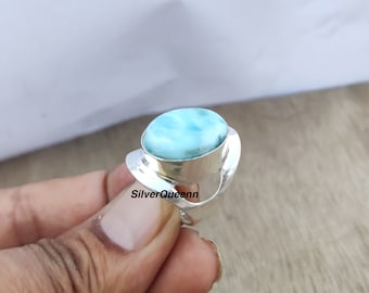 May include: A silver ring with a blue and white oval gemstone. The ring has a unique, curved design.