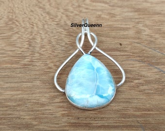 May include: A silver pendant with a blue and white gemstone in a teardrop shape. The pendant is set in a silver frame with a delicate, interwoven design.
