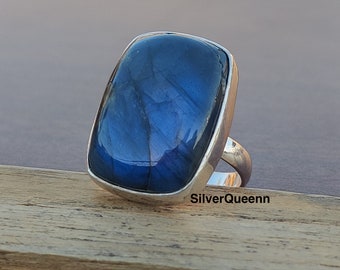 Può includere: Un anello d'argento con una grande pietra rettangolare di labradorite blu. L'anello è incastonato in una semplice fascia d'argento.