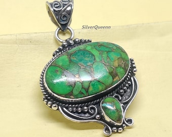 May include: A silver pendant with a large, oval-shaped green stone with brown veining. A smaller, teardrop-shaped green stone is below the larger stone. The pendant has a decorative silver bail and ornate silver detailing around the stones. The text "SilverQueenn" is visible.