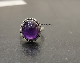 May include: A silver ring with a purple amethyst gemstone set in a bezel setting. The ring has a rope-like design around the edge of the bezel.