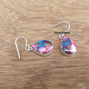 Può includere: Un paio di orecchini a goccia con montatura in argento. Gli orecchini presentano un vivace mix di rosa, blu e oro. Il testo "SilverQueenn" è visibile. Un accessorio elegante.