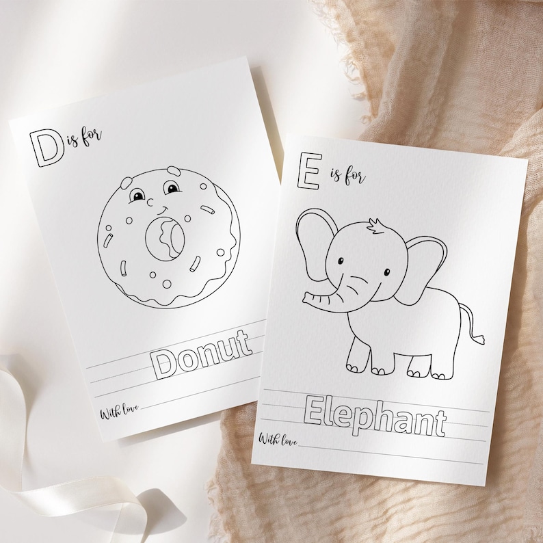 May include: Two white cards with black line drawings. One card says "D is for Donut" with a cartoon donut illustration. The other card says "E is for Elephant" with a cartoon elephant illustration. Both cards have the words "With love" at the bottom.