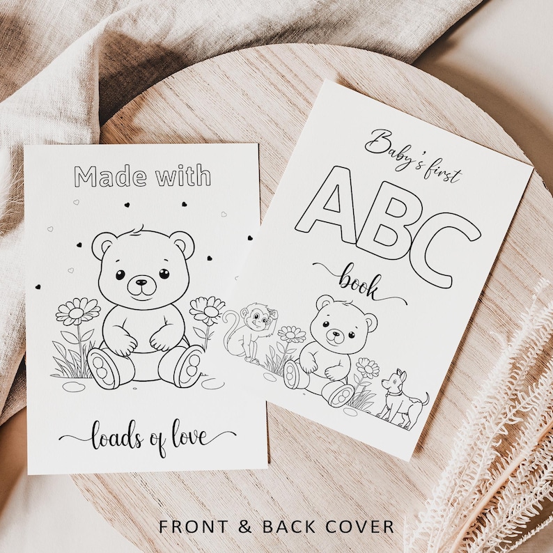 May include: Two black and white baby books with illustrations of a teddy bear, monkey, and dog. One book reads "Made with loads of love" and the other says "Baby's first ABC book". The words "Front & Back Cover" are at the bottom.