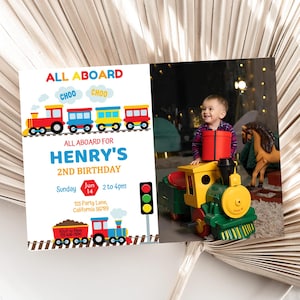 Peut inclure: Une invitation d'anniversaire sur le thème du train. L'invitation indique "TOUS À BORD" et "TOUS À BORD POUR LE 2E ANNIVERSAIRE D'HENRY". Un enfant est montré avec un train jouet. L'invitation comprend la date, l'heure et le lieu.