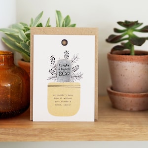 Peut inclure: Une carte de remerciement avec une illustration dessinée à la main d'une plante en pot. La plante a un petit caillou gris avec le texte "thanks a bunch" dessus. La carte porte le texte "we couldn't have done it without you! thanks a bunch, laura!"
