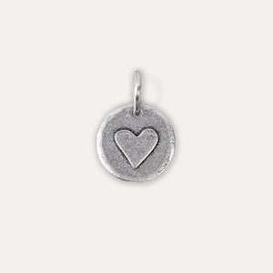 Peut inclure: Un charme en argent en forme de cercle avec un c&oelig;ur en relief au centre.