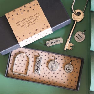 Miniaturowy brelok Lucky Charms z gwiazdkami „Believe”, czterolistną koniczyną „Good luck” i podkową