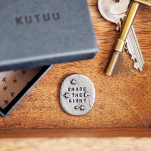 May include: A silver token with the words "Chase the Light" engraved on it. The token is surrounded by small stars and a heart.
