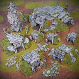 May include: A set of miniature stone structures, including standing stones, platforms, and small buildings, are arranged on a grassy, moss-covered terrain. The grey stone pieces have intricate carvings and are set against a backdrop of brown and green.