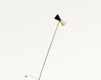 May include: A gold floor lamp with a black and white shade. The lamp has a long, thin stem and a round base.