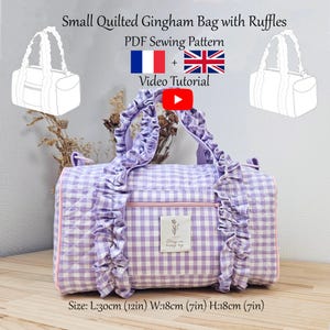 Könnte beinhalten: Eine kleine, gesteppte Gingham-Tasche mit Rüschen in einem lila-weißen Karomuster. Die Tasche hat einen rosa Reißverschluss und Besatz sowie ein Etikett mit der Aufschrift "Stay in happy day". Maße: 30 cm lang, 18 cm breit und 18 cm hoch.