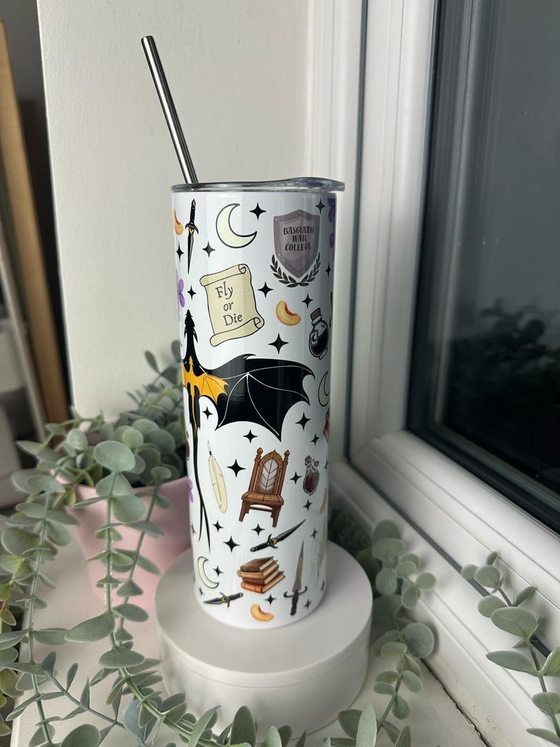 Op de afbeelding: Een witte tumbler met een zwart-wit ontwerp met een draak, een kroon, een veer, een boek, een dolk, een flesje met een toverdrank, een halve maan, sterren en de tekst "Fly or Die" en "Hogwarts Hall College".