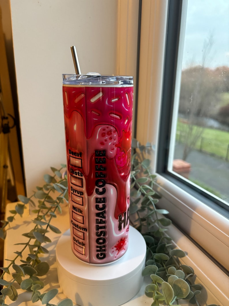 May include: A pink and red stainless steel tumbler with a graphic of a dripping ice cream cone and the text "Ghostface Coffee". The tumbler has a lid and a straw.