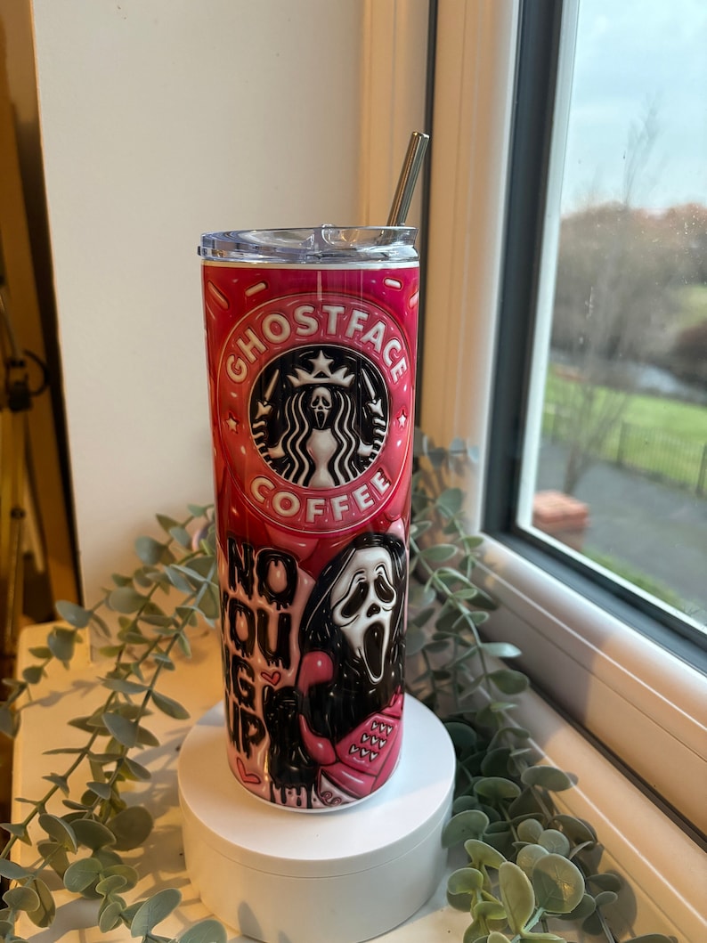 May include: A pink and black stainless steel tumbler with a Ghostface design from the Scream movie franchise. The tumbler features a Starbucks logo with the words "Ghostface Coffee" and a Ghostface mask with a pink phone. The text "No You Hang Up" is written on the side of the tumbler.
