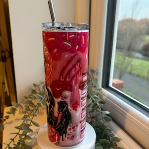 May include: A pink and white stainless steel tumbler with a graphic of a cartoon character with a dripping red heart and the text "Don't Be A D*ck" on the side. The tumbler has a clear lid and a stainless steel straw.