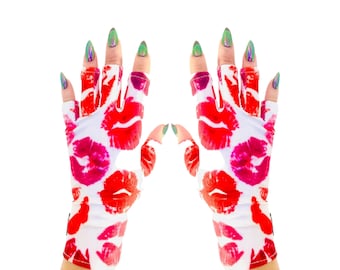 May include: Fingerless white gloves with a repeating pattern of red and pink lipstick kiss marks. The gloves are shown against a white background. The nails are painted with a holographic green polish.