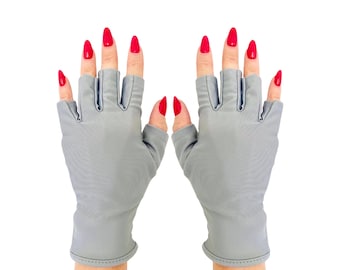 Puede incluir: Un par de guantes sin dedos de color gris claro hechos de una tela suave y flexible. Los guantes presentan un diseño de dedos abiertos que deja al descubierto las puntas de los dedos, cubriendo la mano hasta la muñeca con un dobladillo limpio.
