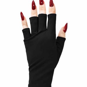May include: Black fingerless gloves with cut-out sections for the fingers. The gloves are worn with long, pointed, red fingernails. The gloves are made of a soft, stretchy material.