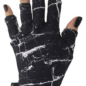 Könnte beinhalten: Fingerlose Handschuhe mit Marmor-Muster in Schwarz und Weiß mit einem schwarzen Band am Handgelenk, auf dem "ManiGlove" steht.