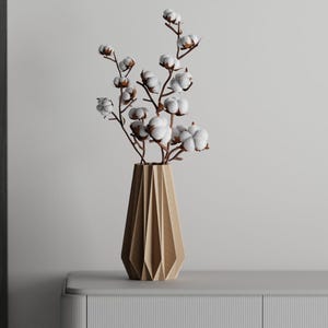 May include: A wooden vase with a geometric design holds a bouquet of white cotton flowers.