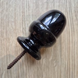 May include: Black ceramic finial with a screw for attaching to furniture or other objects.