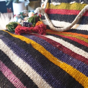 May include: A colorful striped woven throw blanket with fringe tassels. The blanket is made of natural fibers and has a rustic, handmade look.