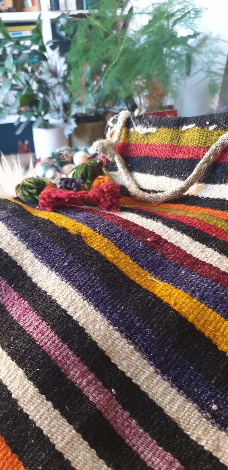 May include: A colorful striped woven throw blanket with fringe tassels. The blanket is made of natural fibers and has a rustic, handmade look.