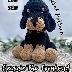 May include: A handmade crochet Coonhound dog in black and tan. The dog has floppy ears, a tan muzzle, and tan paws. The text "LOW SEW" is in a white circle, and "Crochet Pattern" is written vertically. The dog's name, "Clemmie The Coonhound", is also displayed.