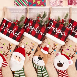 Könnte beinhalten: Fünf personalisierte Weihnachtsstrümpfe mit den Namen Rachel, Sophia, Jasper und Kristen. Jeder Strumpf hat eine rot-schwarz karierte Manschette und einen Körper aus Jute mit Rentier- und Lichterketten-Designs. Die Strümpfe zeigen Gesichter von Schneemann, Weihnachtsmann, Bär und Eisbär.