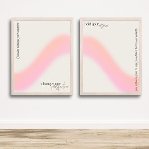 Puede incluir: Dos impresiones enmarcadas con fondos degradados en rosa y blanco. La impresión de la izquierda tiene el texto "if you can't change your situation change your perspective". La impresión de la derecha tiene el texto "hold your vision you will transform in ways you didn't know were possible".