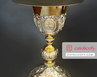 May include: A gold and silver chalice with intricate engravings. The chalice has a round base, a tall stem, and a cup with a decorative design. The chalice is used in religious ceremonies.