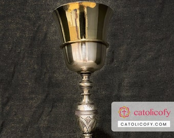 May include: A silver chalice with an ornate design. The chalice has a round base with a stem that flares out at the top. The chalice is decorated with floral patterns.
