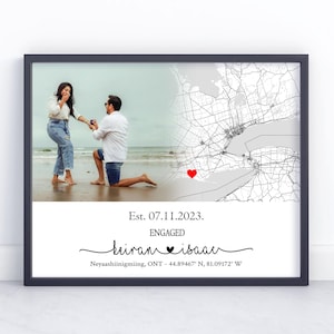 May include: Framed photo print featuring a couple on a beach, with a map overlay and text. The text reads "Est. 07.11.2023. ENGAGED hiram isaac Neyaashiinigmiing, ONT - 44.89467 N, 81.09172 W". The map has a red heart marker.