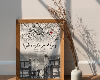 May include: A black and white photo of a couple on a bridge with a city map in the background. The map has a red heart marking the location where the couple got engaged. The text "Where she said Yes - Liam & Katie - London, 24 December 2022" is written below the map.