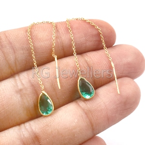Puede incluir: Un par de pendientes de cadena de oro con piedras preciosas verdes en forma de lágrima. Los pendientes cuelgan y tienen un diseño de cadena delicado.