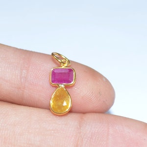 May include: Gold pendant featuring a teardrop-shaped yellow gemstone and a rectangular pink gemstone.